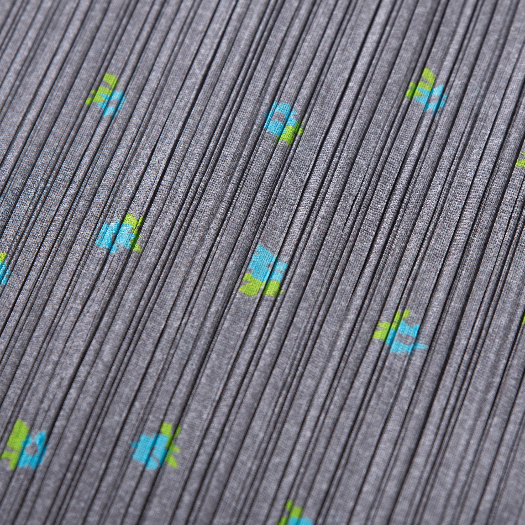 Used PLEATS PLEASE ISSEY MIYAKE side-slit skirt in gray with a floral print. Women's bottoms.