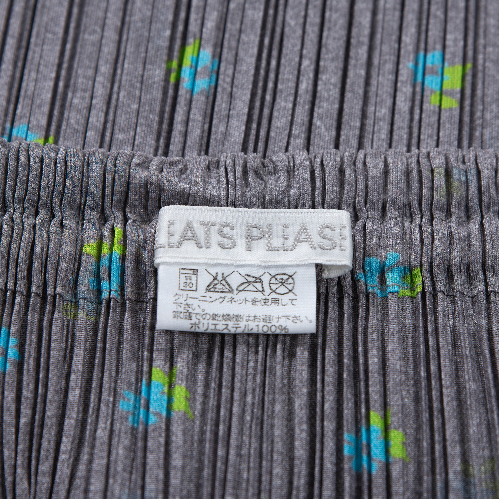 Used PLEATS PLEASE ISSEY MIYAKE side-slit skirt in gray with a floral print. Women's bottoms.