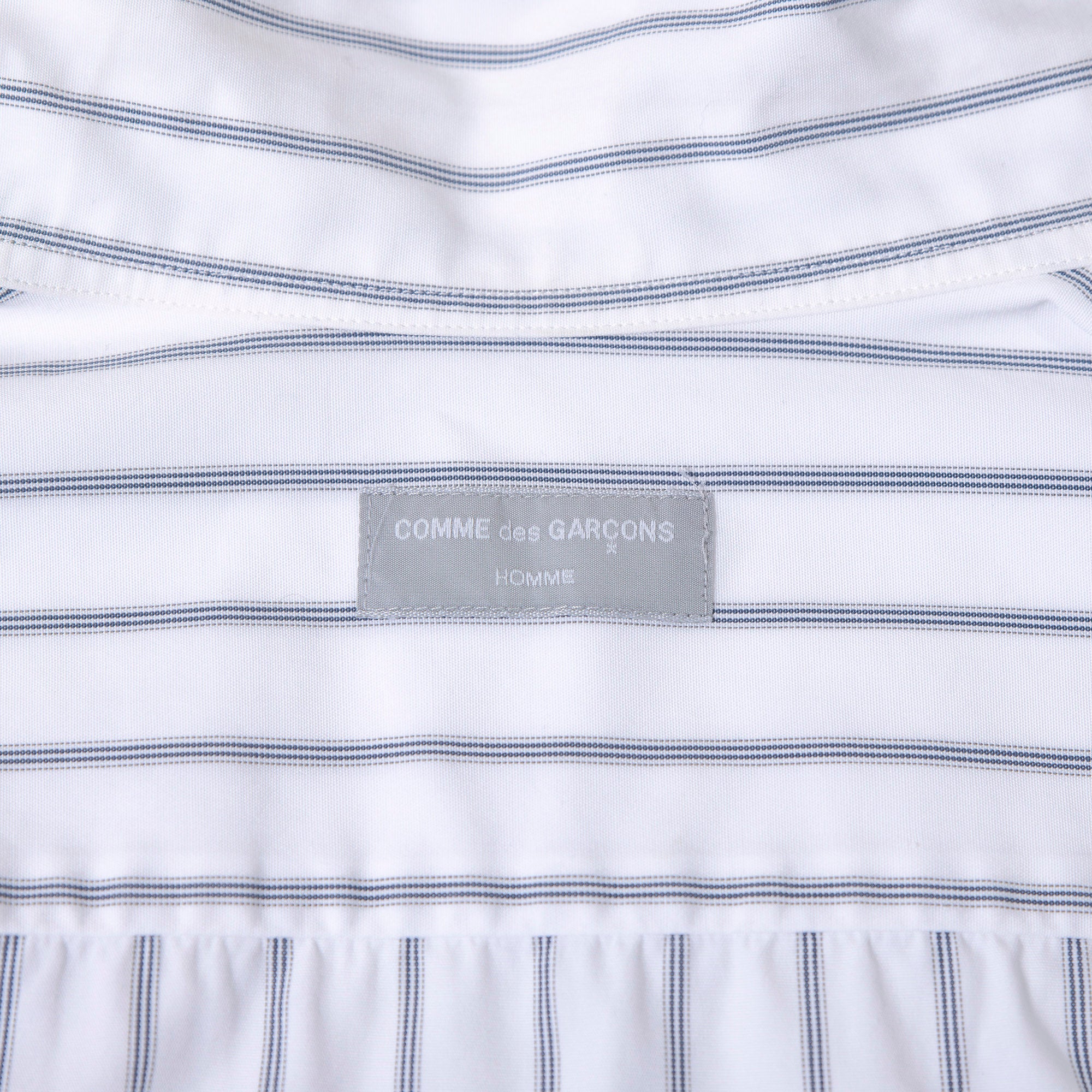 Comme des Garçons striped shirt with a boxy silhouette and long sleeves. This 90s white shirt features an open collar and is designed by Keiichi Tanaka of Tanaka Homme.