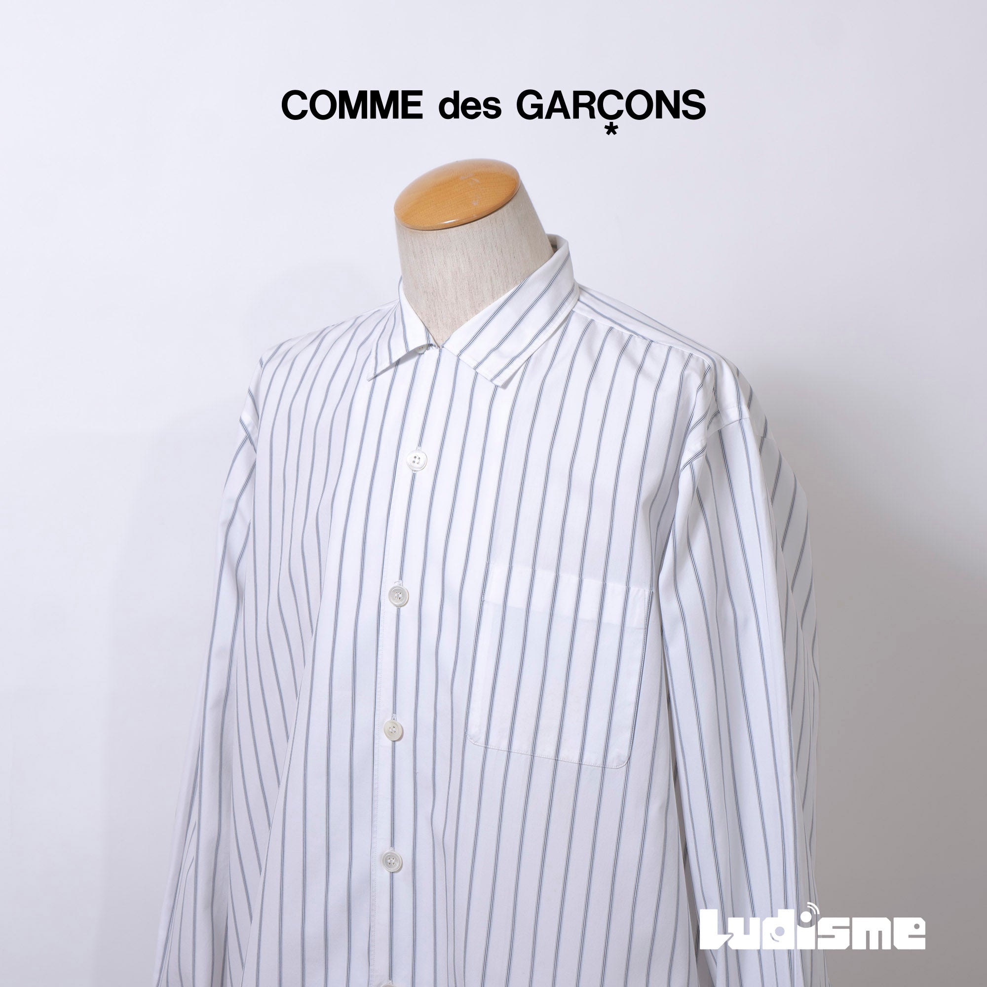 Comme des Garçons striped shirt with a boxy silhouette and long sleeves. This 90s white shirt features an open collar and is designed by Keiichi Tanaka of Tanaka Homme.